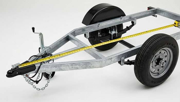 Tape measure stretched from a trailer coupler to the end of the axle to check axle alignment