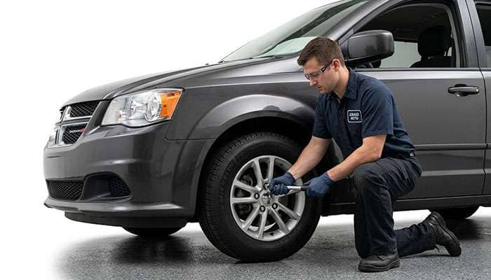 Mechanic wearing gloves using a wrench to install a tire on a car in a service shop in Indianapolis, IN.