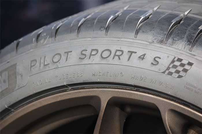 Close-up of a Michelin Pilot Sport 4 S tire mounted on a bronze alloy wheel showing tire branding and tread pattern
