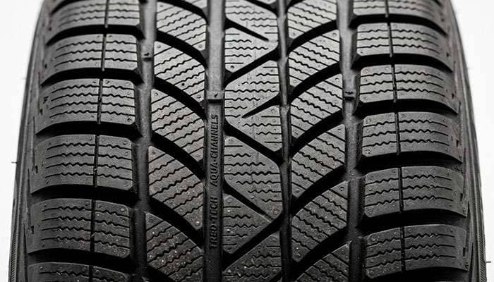 Close-up of modern tire tread showing siping pattern and tread block design for safety performance