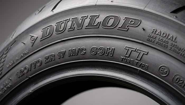 Detail close-up of motorcycle tire sidewall showing speed rating load index and TT TL markings