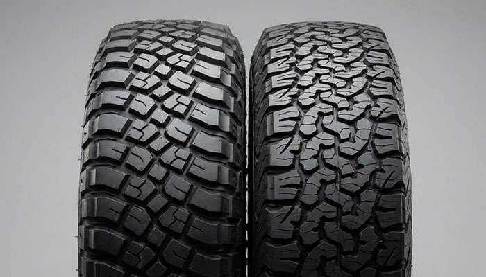 Close-up comparison of mud terrain and all terrain tires on off-road vehicles with text overlay Mud Terrain vs All Terrain