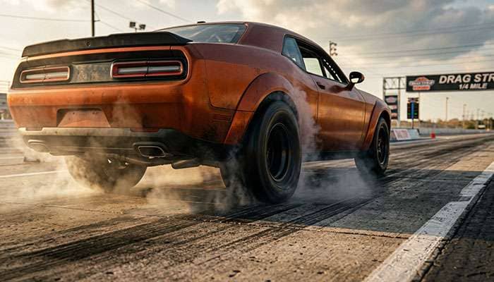 Muscle car drag strip launch showing rear drag radial tires under load at hard acceleration