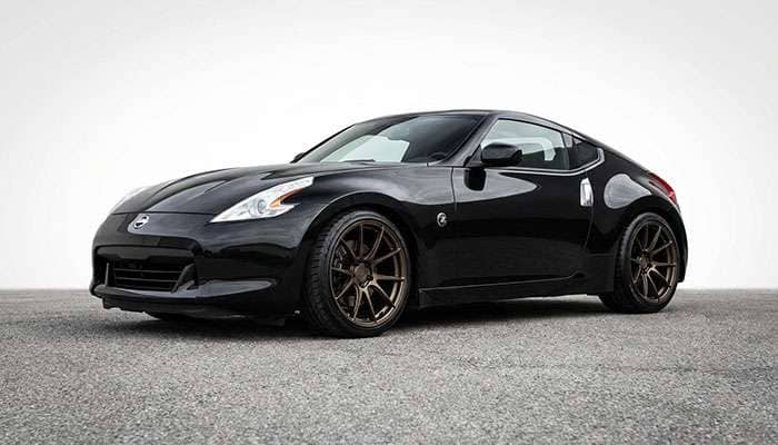 Black Nissan 370Z with bronze aftermarket wheels and low-profile tires parked outdoors on pavement