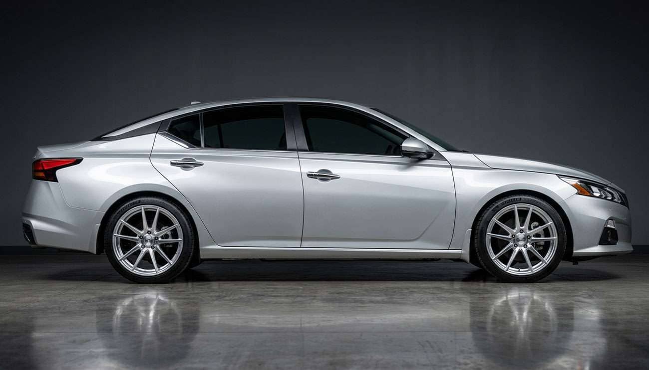 Nissan Altima with aftermarket alloy wheels on a clean studio floor showing full vehicle profile.