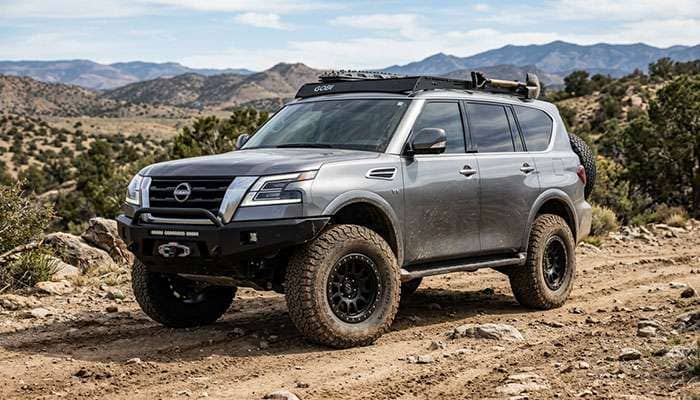 Nissan Armada SUV fitted with rugged Ford Bronco wheels parked outdoors on a dirt surface.