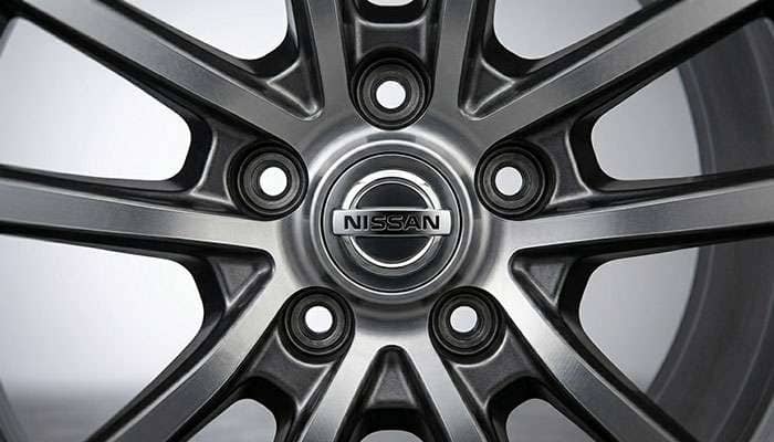 Close-up of a Nissan wheel showing lug nut sockets and the Nissan emblem on the center cap.