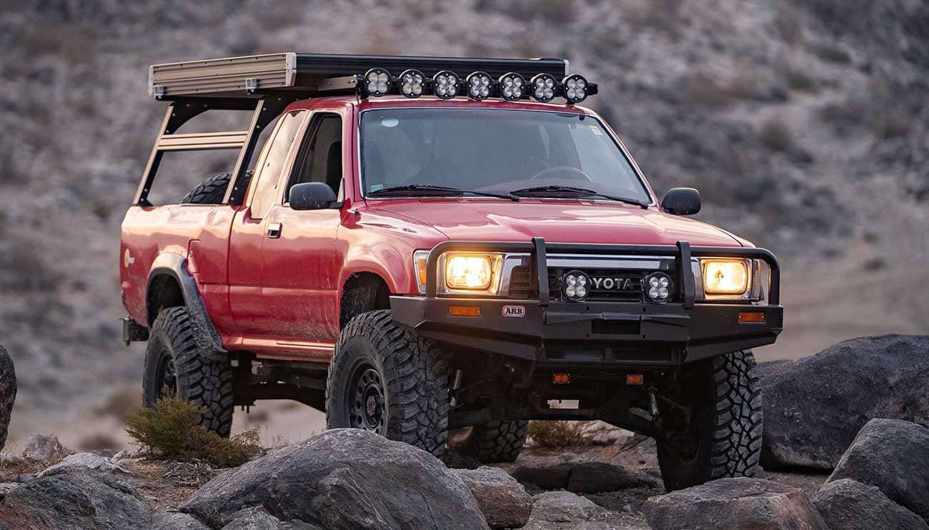 Close-up of rugged off-road Nomad Wheels on a vehicle driving through sandy terrain at sunset