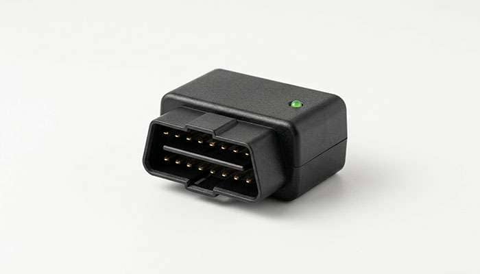 Small OBD-II telematics device used by insurance usage-based driving programs on a clean white backdrop