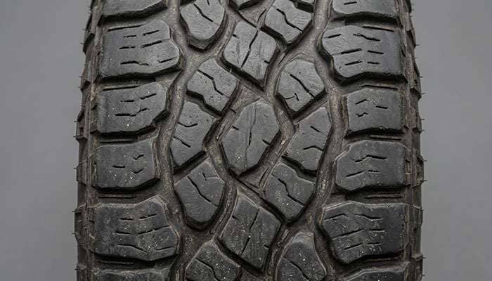 Close-up of off-road tire tread blocks showing wear patterns from daily highway driving