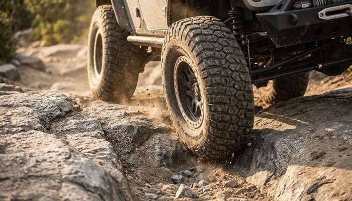 Close-up of an off-road vehicle's tires gripping rocky, uneven terrain during an expedition