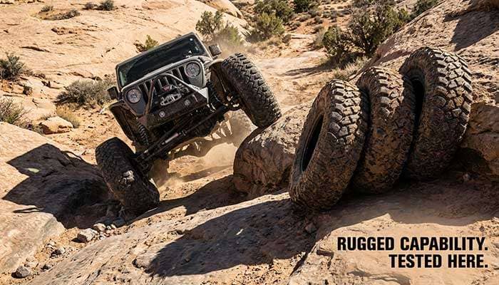 Off-road vehicle climbing rocks next to three large rock crawling tires with bold text 'Best Rock Crawling Tires.'
