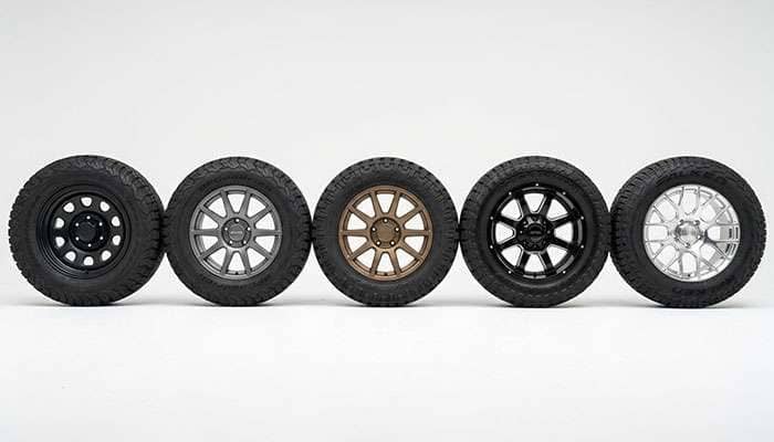 Five different off-road wheels from popular brands displayed on a clean white studio surface showing variety of styles and finishes