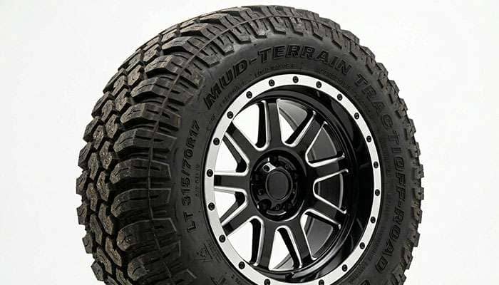 Off-road truck wheel close-up with mud-terrain tire showing aggressive lug pattern and rugged construction