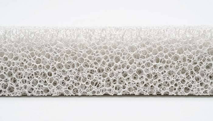 Close-up of an open-cell polyurethane acoustic foam strip used inside a quiet tire, studio photo