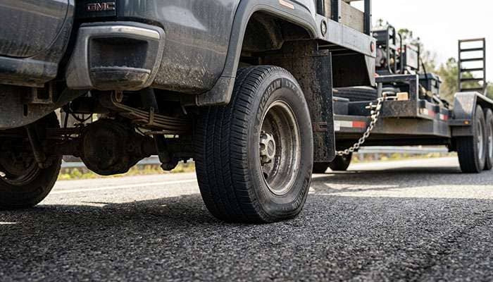 Rear tire of a loaded pickup truck showing sidewall bulge under heavy towing load