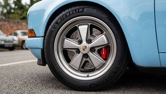 Lightweight aluminum performance wheels on classic sports car showing brake caliper clearance