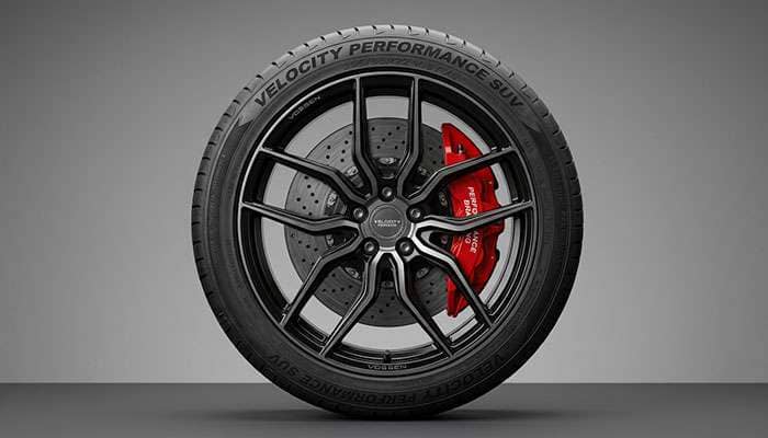 Performance SUV tire mounted on a multi-spoke alloy wheel showing the sidewall detail and large performance brake caliper visible behind the spokes