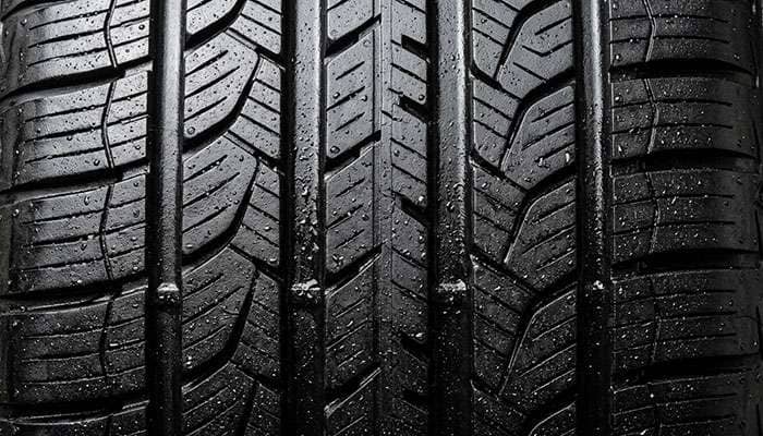 Close-up of performance tire tread pattern showing asymmetric design and wide circumferential grooves for wet handling