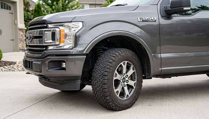 Full-size pickup front wheel turned to full steering lock showing tire clearance to the fender liner and front valance