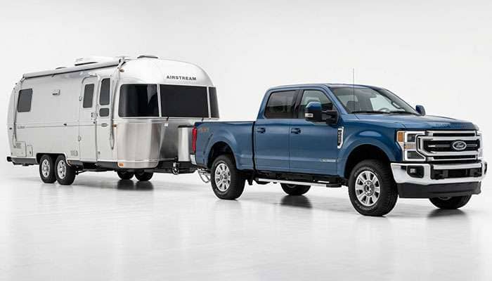 Pickup truck pulling a large travel trailer with the rear tires visible under towing load
