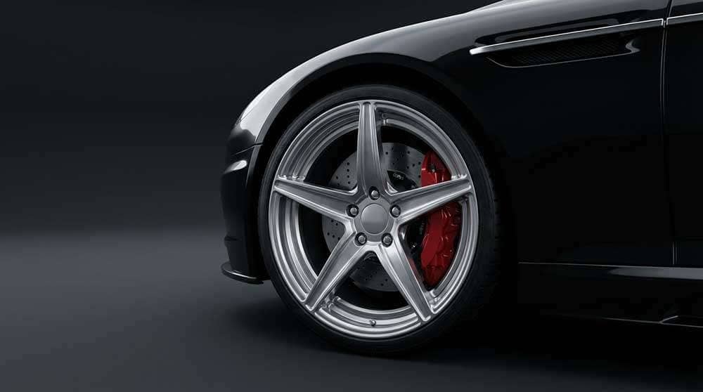Close-up of a sleek black car showcasing a polished forged wheel with a five-spoke design and large brake disk