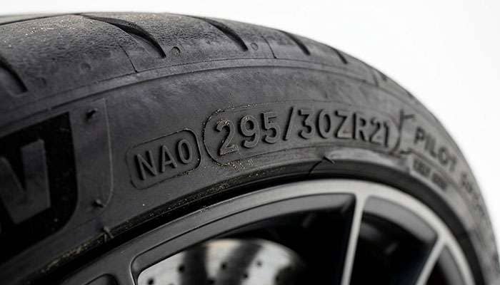 Close-up of an NA0 Porsche approval code molded into a performance tire sidewall beside the ZR size marking