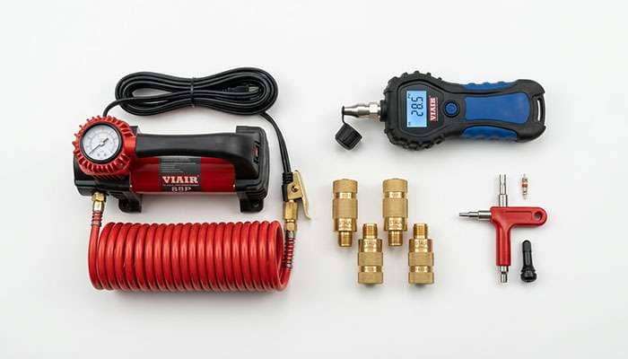 Portable air compressor tire deflator and digital pressure gauge laid out as essential tools for airing down tires safely