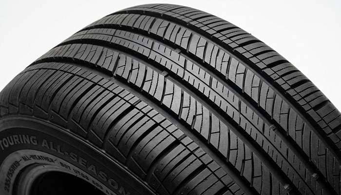 Close-up of a quiet touring tire tread pattern showing variable pitch blocks and dense siping