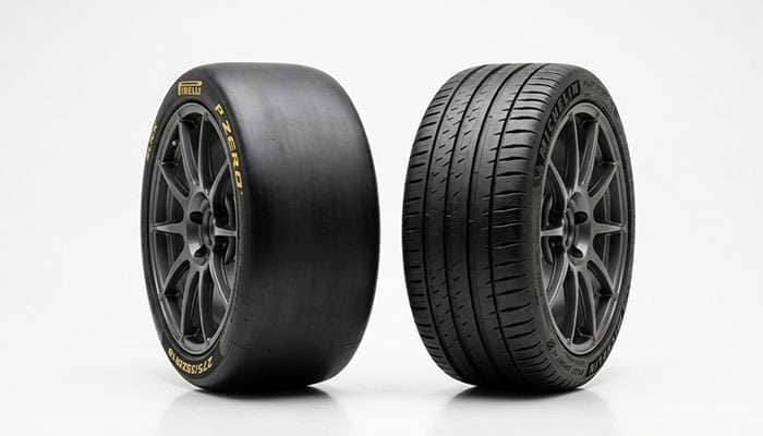 A smooth racing slick tire beside a grooved street tire