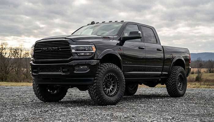 Black Ram pickup truck with large tires parked on gravel showing 37-inch tire fitment on 4th and 5th gen Ram trucks