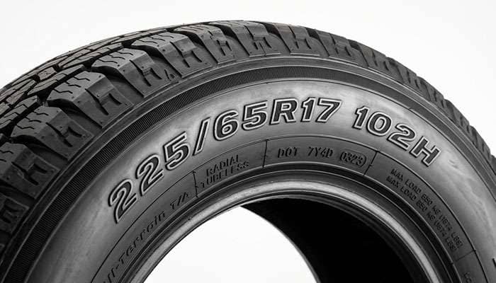 Close-up of a tire sidewall showing the 225/65R17 102H load index and speed rating