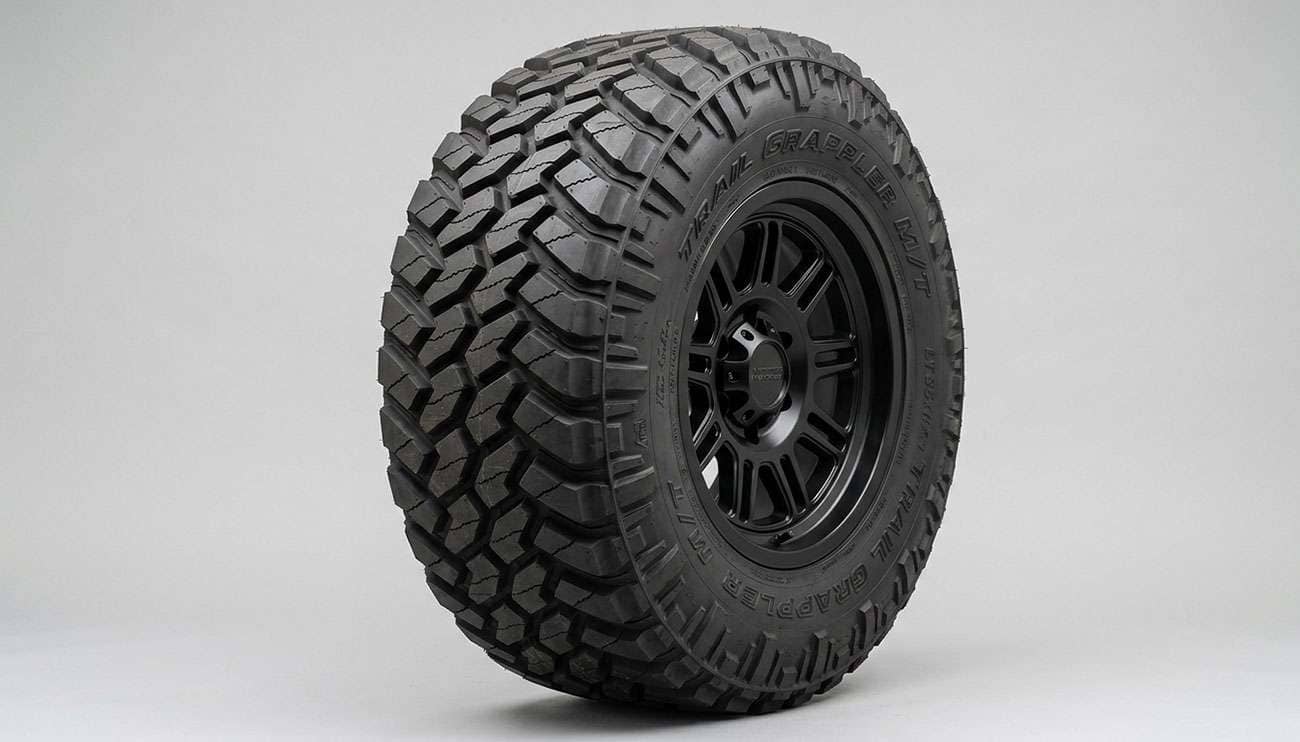 Aggressive off-road tire showing reinforced sidewall construction wide tread voids and detailed siping on the tread blocks