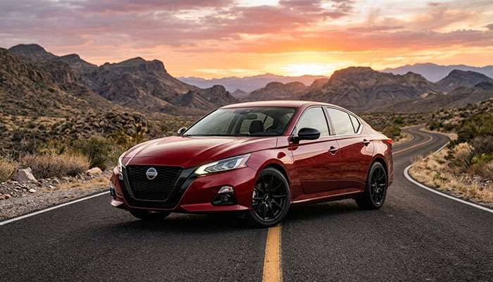 2021 red Nissan Altima parked on road with black XXR 559 wheels and mountainous desert background at sunset.