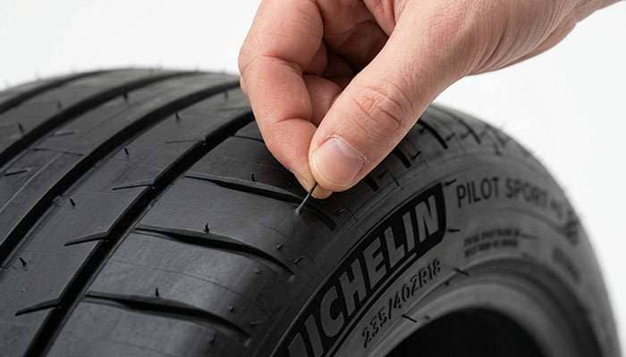 Hand pinching and removing a rubber vent spew from a new tire sidewall