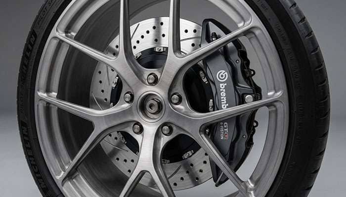 Close-up of a forged aluminum wheel showing brake caliper clearance with a large performance brake rotor and caliper visible through the spokes