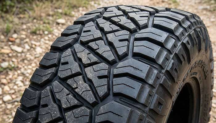 Close-up of Nitto Ridge Grappler hybrid tread pattern showing variable pitch center blocks and aggressive shoulder lugs with Z-grooves