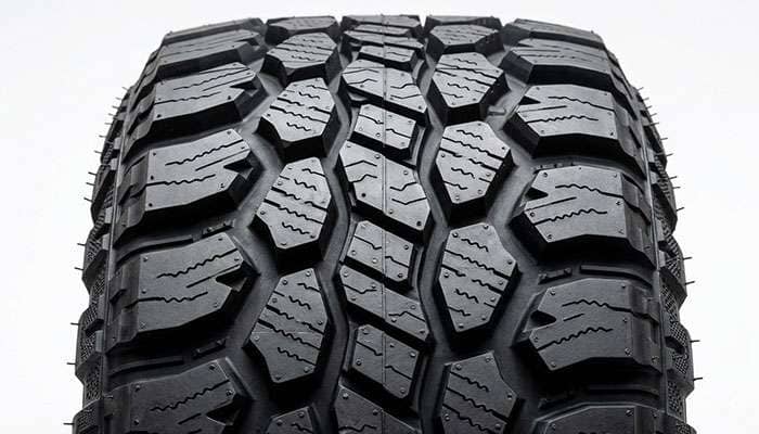 Close-up of a rugged terrain R/T tire showing aggressive shoulder lugs, sidewall biters, and tighter center tread blocks