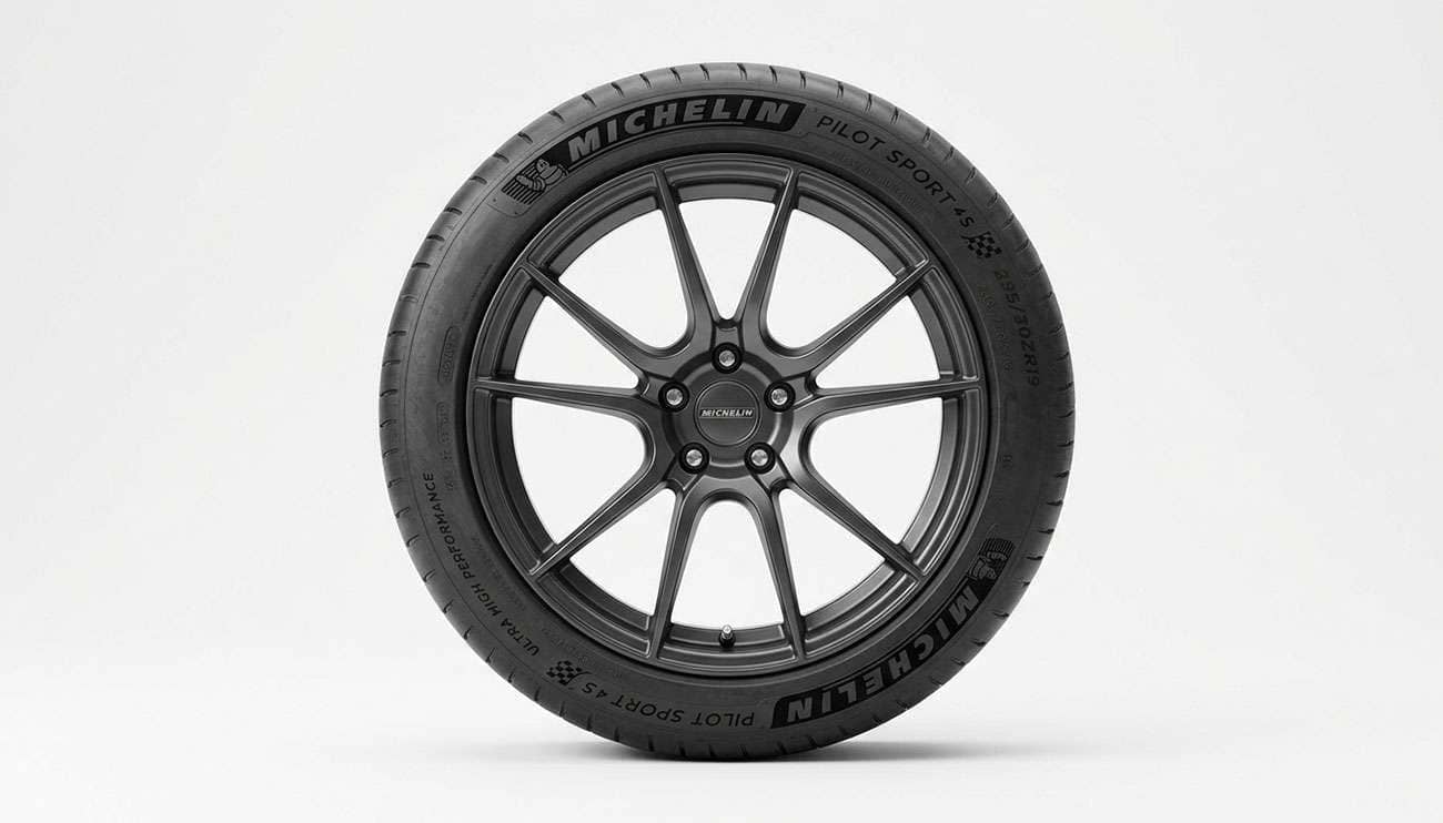 Front view of a mounted performance tire showing its full section width and narrower tread contact band on a clean white studio background
