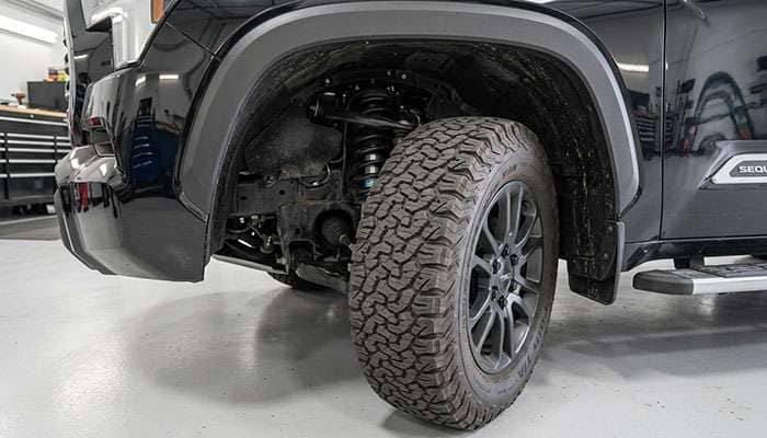 Front wheel well of a Toyota Sequoia showing clearance between a 33-inch all-terrain tire and the fender liner with the wheels turned to full lock
