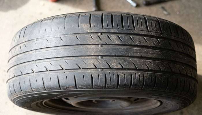 Close-up of a tire showing heavier wear on one shoulder compared to the opposite shoulder of the same tread