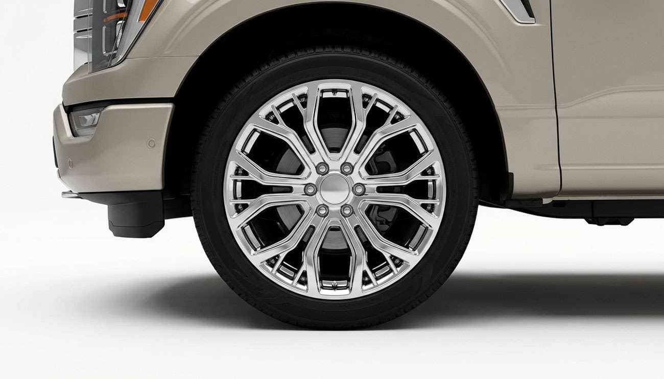 Close-up of a shiny snowflake-style wheel mounted on a beige truck against a dark background