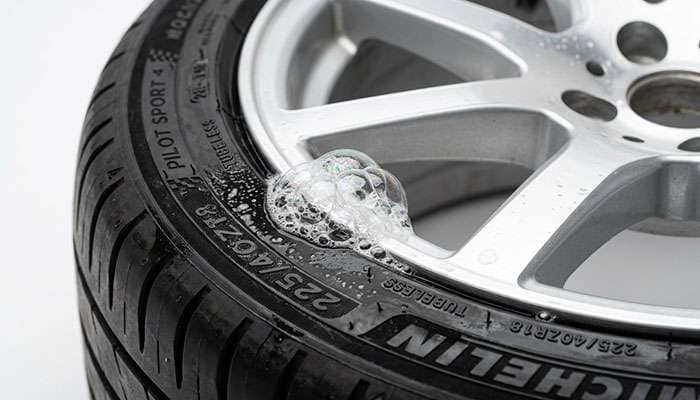 soapy water sprayed along the bead seam where a tire meets an aluminum wheel producing a growing dome of bubbles from a bead leak