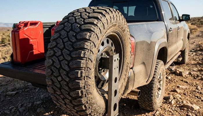 Spare tire mounted on a Toyota Tundra tire carrier with a red fuel container in the truck bed