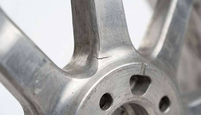 Detail view of a fatigue crack forming at the base of a wheel spoke where it meets the center disc