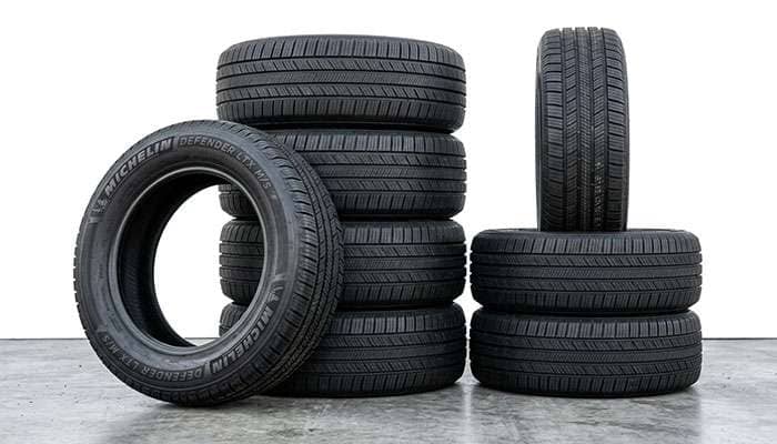 Stacked and arranged new tires suitable for Dodge Grand Caravan performance enhancement outdoors.