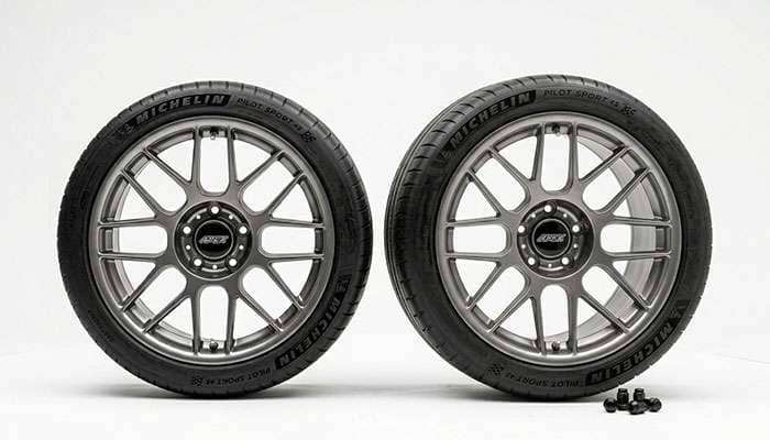 Narrower front wheel beside a wider rear wheel illustrating a staggered fitment on a white studio backdrop