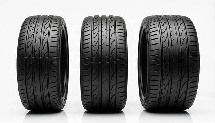 Three performance tires standing upright on a clean white studio surface showing different widths for staggered front and rear fitment