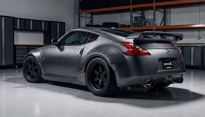 Close-up of a modified car with staggered wheels showing wider rear tires and custom fender flares in a garage