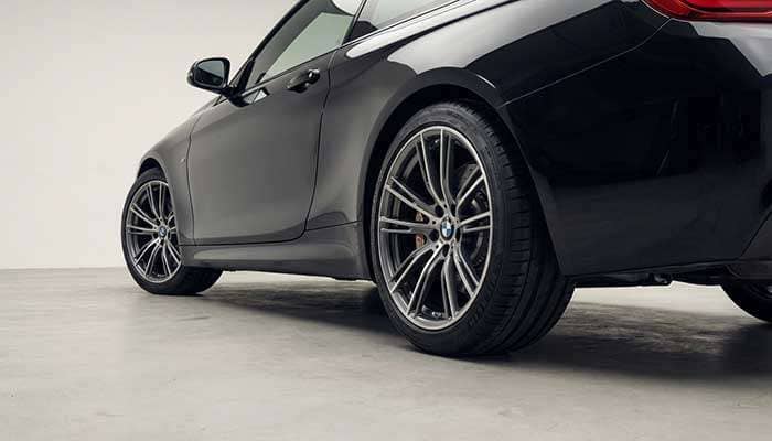 Close-up of a black car with staggered wheels and text about the pros and cons of staggered wheels